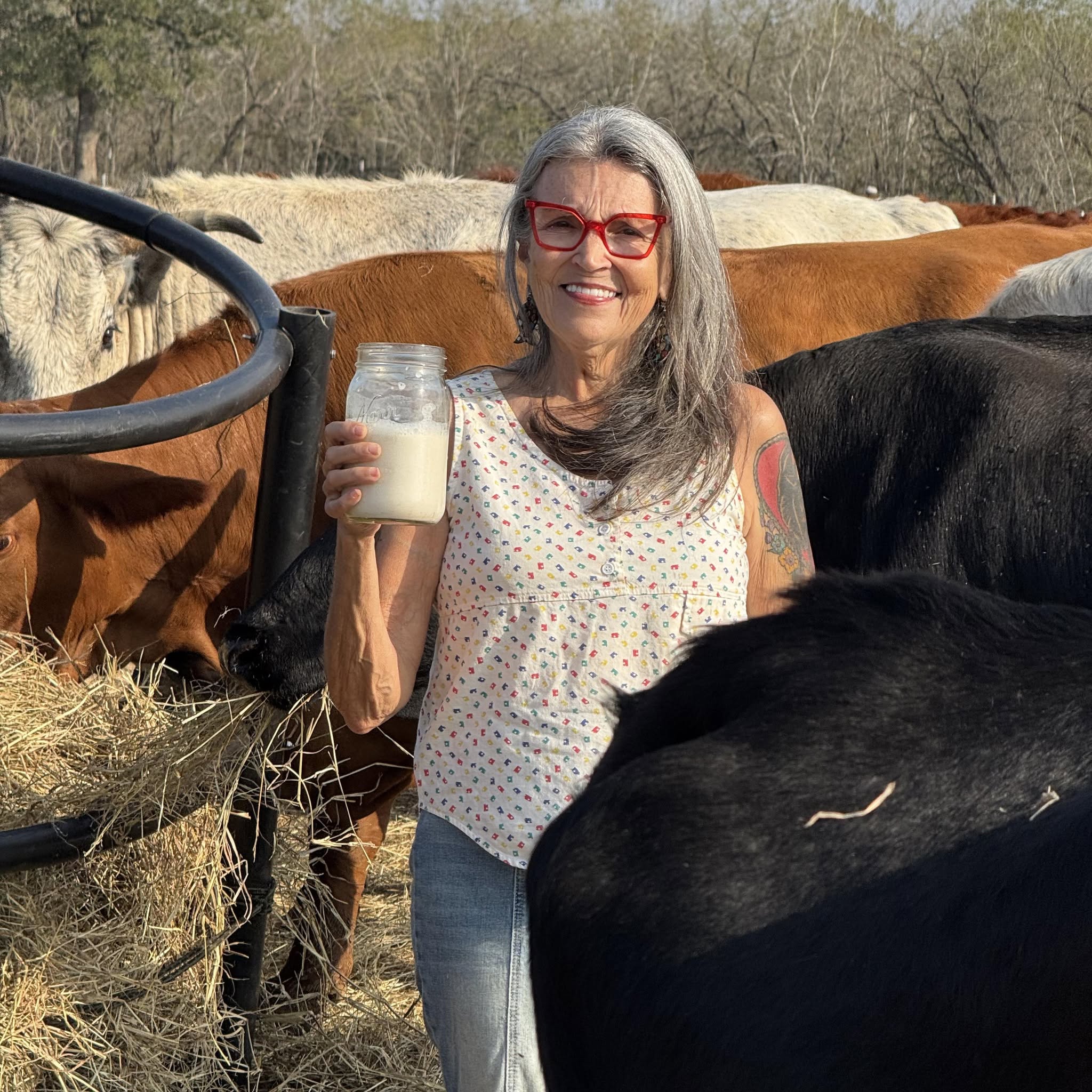 renee-facebook-image Renee standing surrounded by cows holding a jar of vegan milk